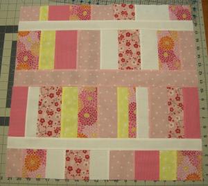 Pink, yellow and white strips assembled into a preemie quilt top.